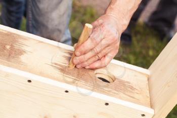 Birdhouse made of wood is under construction, carpenter adds detail