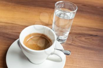 A cup of espresso coffee and small glass of fresh water