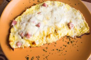 Freshly roasted omelet with ham and cheese on a plate. Breakfast theme