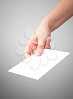 Female hand with the white virtual card on gray background