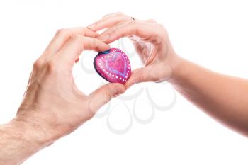 Pink painted handmade heart shaped stone in hands of young Caucasian man and woman isolated on white