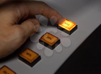 Finger pressing max button on industrial power control panel. Selective focus