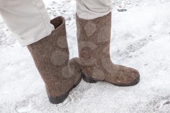 Male feet with Russian gray felt boots on winter road with snow and ice 