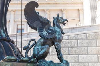 Bronze statue of Griffin. Decoration of old street lamp in front of Austrian Parliament Building, Vienna, Austria. It was erected in 1900. Selective focus