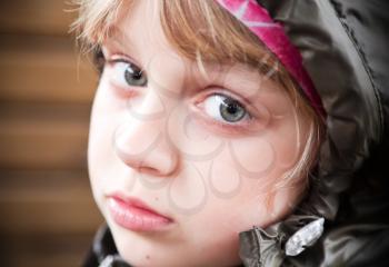 Closeup portrait of a little blond girl in a casual jacket with the hood