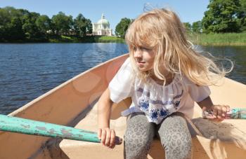 Little blond girl rowing on the boat