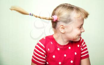 Portrait of laughing little blond girl with funny pigtails