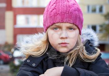 Little beauty blond girl looks thoughtfully into the distance. Outdoor street city portrait.