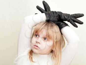 Little blond girl shows a deer with antlers as a black gloves