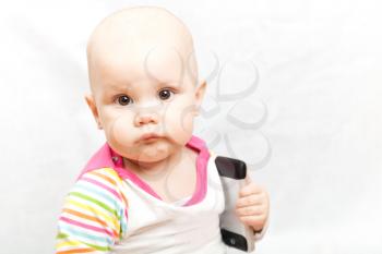 Little baby in casual colorful striped clothing plays with mobile phone