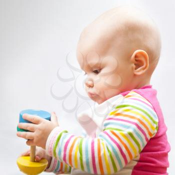 Little baby plays with wooden toy, closeup portrait