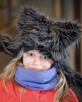Little blond girl in fun artificial fur hat. Closeup portrait