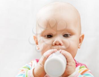 Little brown eyed Caucasian baby with bottle of milk