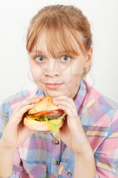Little blond girl with homemade burger on white background