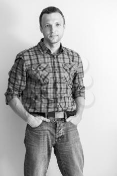 Young Caucasian man in checkered shirt and jeans. Black and white portrait