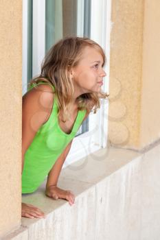 Little blond Caucasian girl in window, outdoor portrait