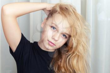 Smiling blond Caucasian girl with long hair, closeup studio portrait