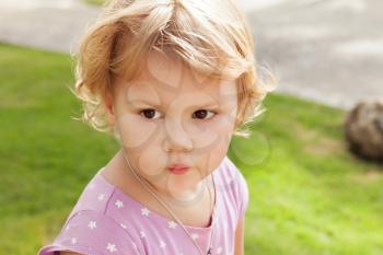 Outdoor closeup portrait of cute Caucasian blond baby girl in a park
