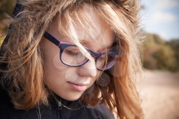 Beautiful blond Caucasian teenage girl in glasses, outdoor close up portrait