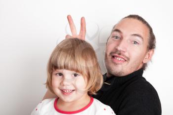 Young man with little blond Caucasian girl, studio portrait over white wall background