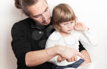 Young man reading book with little Caucasian girl, studio shoot