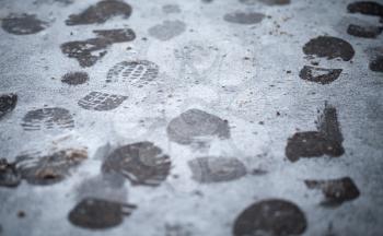 Footsteps in fresh wet snow on asphalt urban road, closeup photo