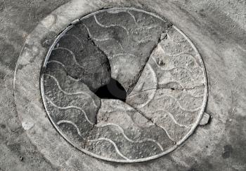 Old broken manhole cover on the asphalt road