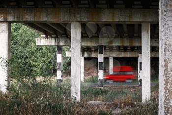 Red van car goes fast under old bridge