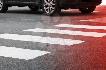 Pedestrian crossing road marking and moving car, photo with red gradient tonal filter, selective focus and shallow DOF