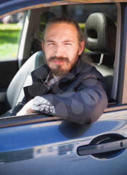 Positive Asian man as a driver of modern Japanese suv, vertical portrait in open car window