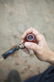Smoking pipe in male hand, top view, outdoor photo with selective focus and vintage tonal correction photo filter, old style effect