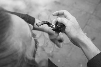 Man smoking pipe, black and white outdoor photo with selective focus