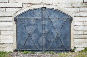 Closed blue metal gate in old stone wall