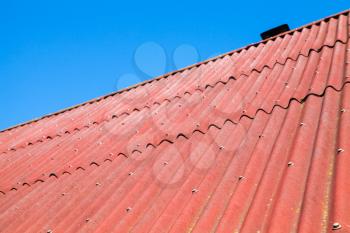Blue sky and red roof made of corrugated cardboard bituminous, background photo texture