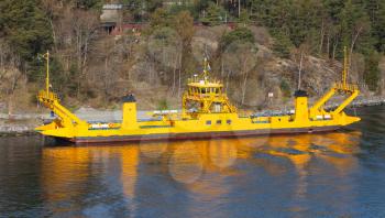 Yellow roro cargo ship goes near an island coast, Stockholm archipelago, Sweden