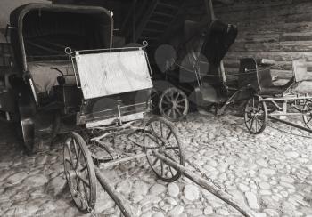 Empty vintage coaches stand in a rural garage, black and white photo