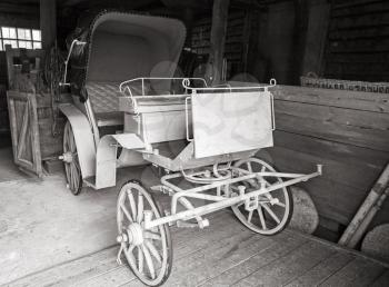 Vintage white coach stands in rural garage, black and white photo