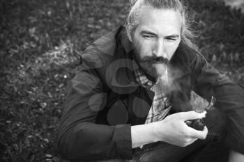 Asian man smoking a pipe, black and white photo with selective focus