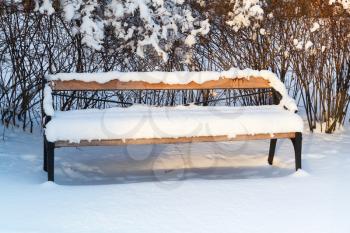 Outdoor wooden bench covered with snow in winter park. Turku, Finland