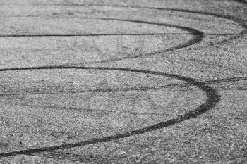 Abstract transportation background, dark tire tracks on gray asphalt road
