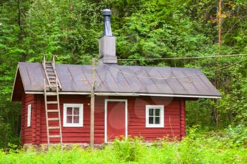 Traditional Scandinavian red wooden house over green forest background. Kotka, Finland