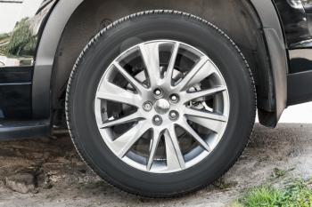 Modern unidentifiable  suv car wheel on rural road, closeup frontal photo