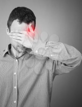 Young adult man with headache. Black and white stylized photo with red local ache spot