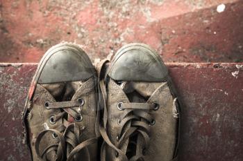 Pair of old sneakers standing on red concrete stairs, closeup photo, top view