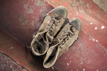 Pair of old sneakers standing on red concrete stairs, top view
