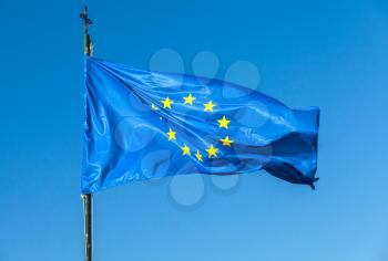 Flag of Europe, or European Flag waving on a flagpole over clear blue sky background
