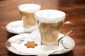 Glass mugs full of Cappuccino stand on wooden table. Close up photo with soft selective focus
