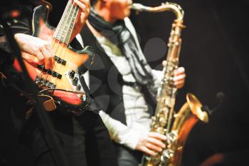 Musical background, guitar player and saxophonist on a stage with colorful illumination, photo with selective focus and retro tonal correction filter effect, old instagram style