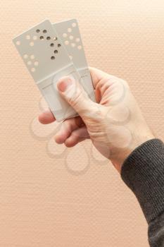 Male hand holds two gray plastic door key cards with holes combination code
