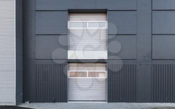 Two level closed gates in gray metal warehouse wall, flat background photo texture
